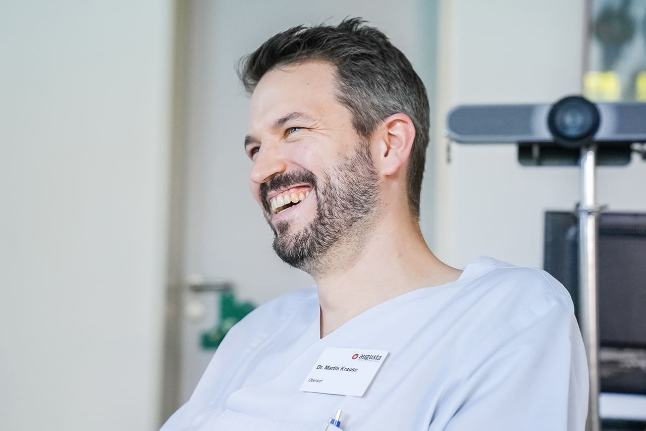 Das Porträt eines lachenden Arztes.