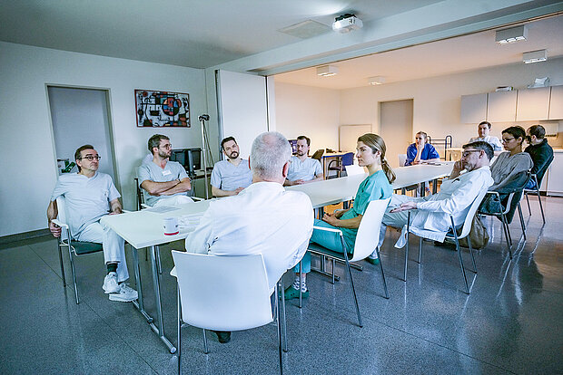 Versammlung von Klinikpersonal an einem langen Tisch.